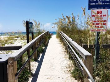 Information sign by walking at beach against sky