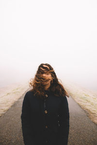 View of woman standing on road against cloudy sky