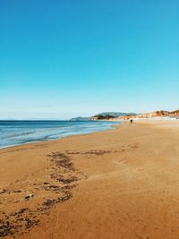 Scenic view of beach against clear blue sky