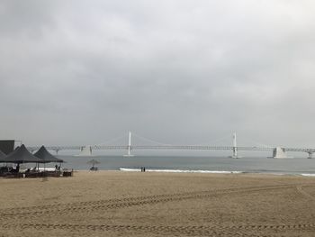 Suspension bridge over sea against sky