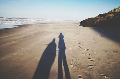 Shadow of people on beach against sky
