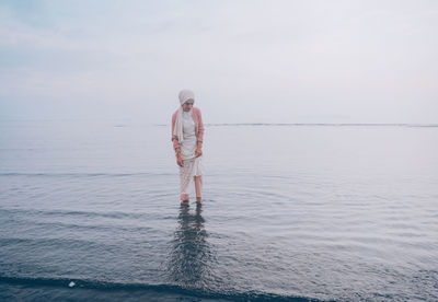 Rear view of man standing in sea against sky