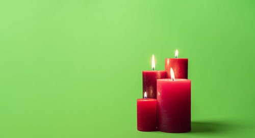 Close-up of burning candle against green background