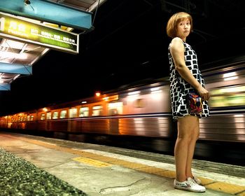 Full length of woman standing by train at railroad station