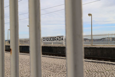 Railroad tracks against sky seen through fence