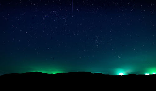 Low angle view of silhouette landscape against star field at night