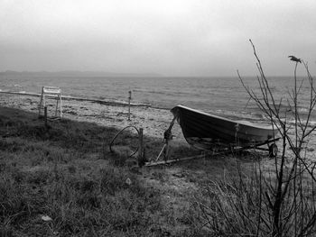 Abandoned boat moored on beach against sky