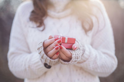 Midsection of woman holding gift while wearing sweater