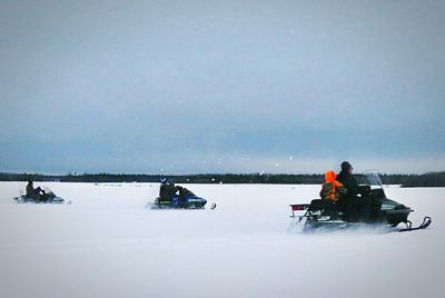 People on boat in winter against sky