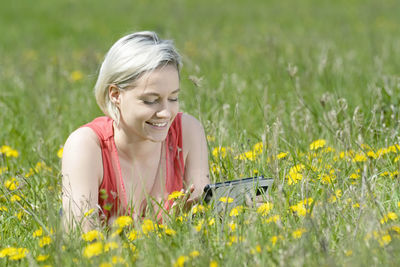 Portrait of smiling woman with yellow flower on field