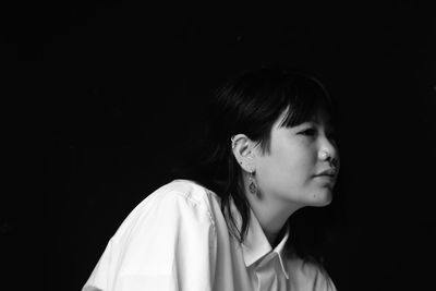 Close-up of thoughtful young woman against black background