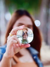 Close-up of woman holding crystal ball against face