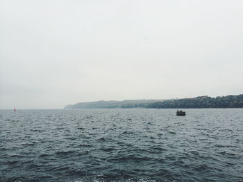 Scenic view of sea and mountains against clear sky