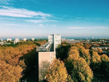 Buildings amidst trees in city against sky