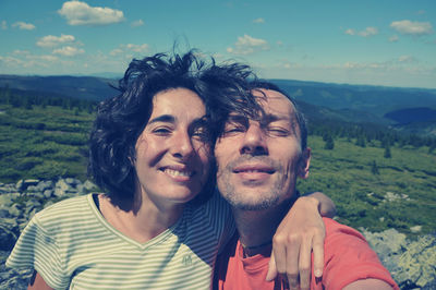 Portrait of loving couple standing on mountain against sky