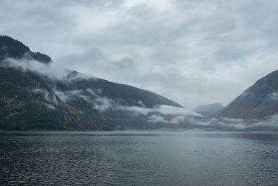 Scenic view of lake by snowcapped mountains against sky