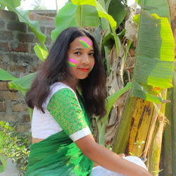 Portrait of a smiling young woman standing against plants