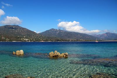 Scenic view of sea and mountains against blue sky