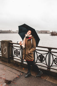 Woman standing by railing against river