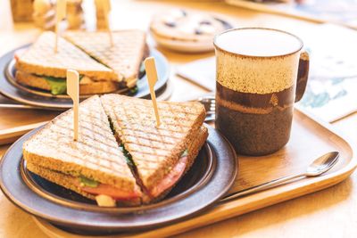 Close-up of toasted sandwiches with coffee on tray at table