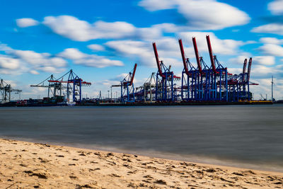 Cranes at commercial dock against sky