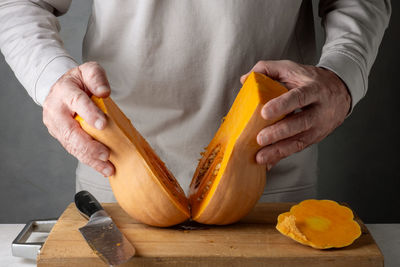 Midsection of man cutting pumpkin