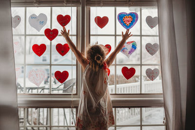 Rear view of woman standing by window