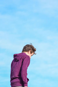 Side view of woman standing against blue sky