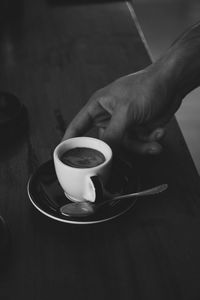 Cropped hand holding coffee on table