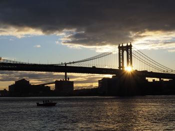 Suspension bridge over river during sunset