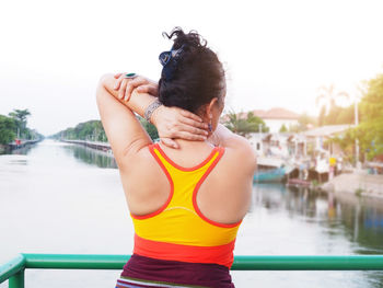 Rear view of woman standing by swimming pool against sky