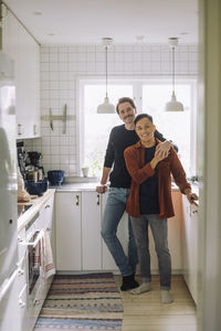 Portrait of smiling gay men standing together in kitchen at home