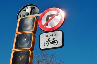 Low angle view of road sign against clear blue sky