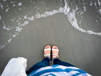 Low section of man standing in sea