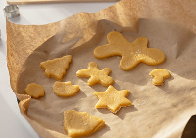 Parchment with raw baked goods in the form of christmas cookies stands on a white table