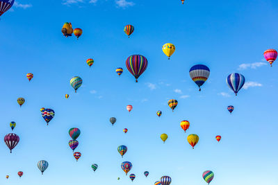 Low angle view of hot air balloons flying against blue sky