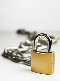 Close-up of padlock with chain over white background