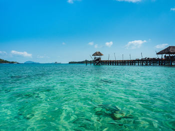 Koh mak island, thailand. scenic clear turquoise water with coral reef and wooden pier landmark.