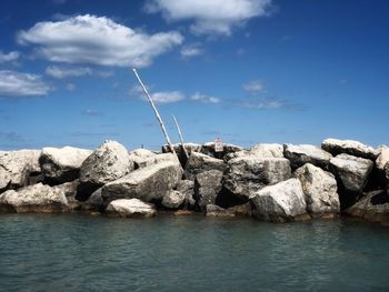 Rock formations by sea against blue sky