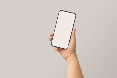 Midsection of person holding smart phone against white background