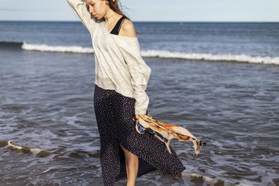 Woman standing on beach against sky