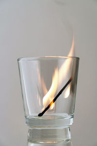 Close-up of burning candle on glass