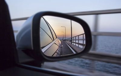Close-up of car on bridge reflecting on rear-view mirror