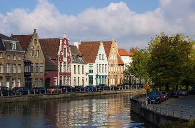 Canal amidst buildings in brugge against sky