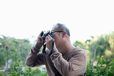 Man photographing against sky