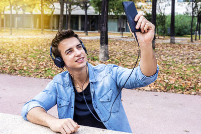 Man listening music while taking selfie in city