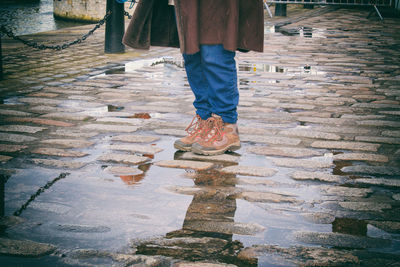 Low section of person standing on puddle at harbor