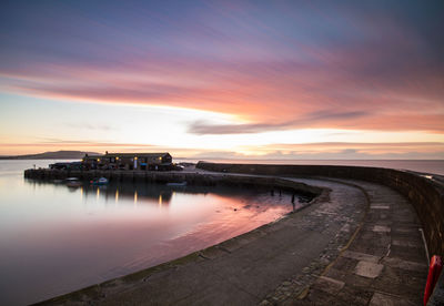 Pier over sea against sky during sunset