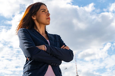 Low angle view of woman looking away against sky