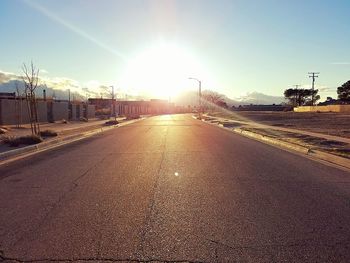 Road by city against sky during sunset